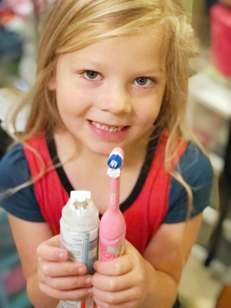 child showing off her toothbrush and toothpaste